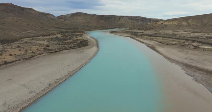 4K video; Slow forward drone flight over a small muddy river in the hills and pampas of southern Argentina