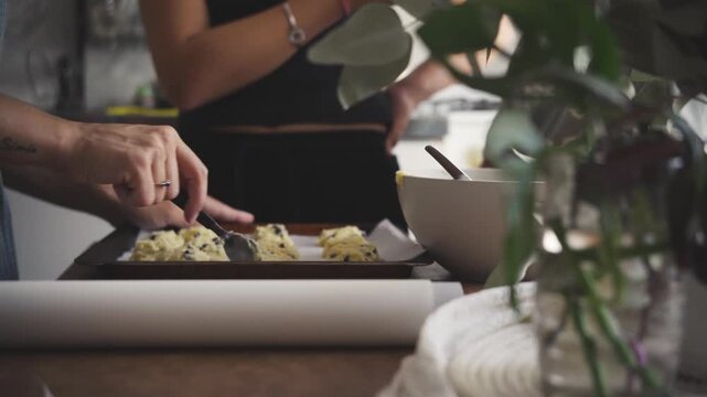 Mother baking cookies at home with her daughters watching the process, focusing on the tactile process of homemade baking and warm family interaction concept