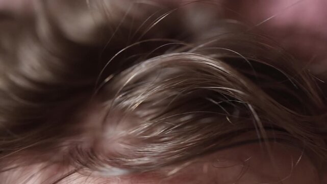 Checking hair for lice the closeup of fingers moving through strands shows careful inspection and the routine search for tiny pests often done when itching or irritation appears