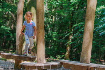 Cute running girl playing on wooden balance beams in forest park © Sergey Novikov