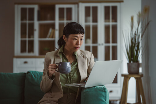 Asian woman working remotely with laptop and coffee