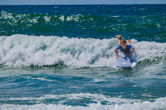Boy catch wave to surf during surfing lesson in ocean school