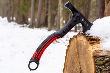 Mała siekiera survivalowa (maleńki toporek) wbita w pniak dębu w zimowym otoczeniu, osadzona jest w pniu dębu pokrytym śniegiem. Siekiera charakteryzuje się solidną, ergonomiczną konstrukcją  © Grzegorz