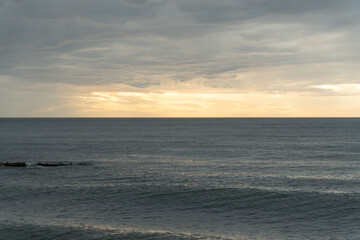 Fototapeta premium Calm Black Sea horizon under layered cloudy sky with soft golden light near sunset, wide seascape with muted blue gray tones and minimal composition. Tourism promotion, wellness branding, travel
