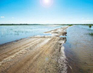 Road flooded and cut off with water crossing asphalt in rural area