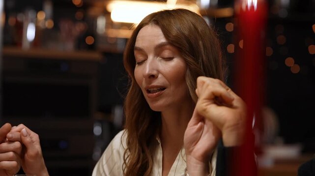 Woman says a prayer with closed eyes while sitting and holding hands