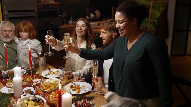 A female guest stands and says a toast and then clinks glasses with family and guests sitting at the table