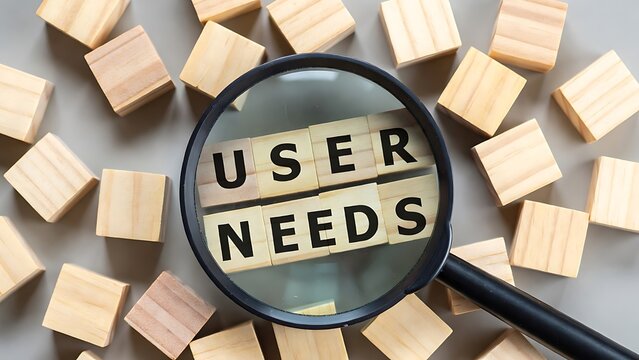 Magnifying glass over wooden blocks spelling 'USER NEEDS' surrounded by more blocks