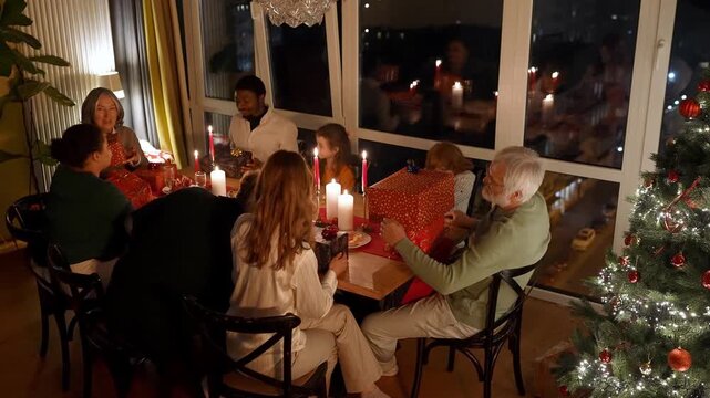 Family and guests sitting at the table shaking gifts