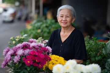 Elderly woman smiling proudly at her vibrant flower stall