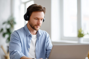 Focused man working with a laptop in a bright room