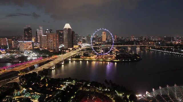 Singapore by Night &ndash; 4K aerial drone footage of marina bay sands, city skyline, skyscrapers, luxury hotels, and river illuminated in financial district (CBD).