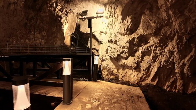Underground waterfall flowing over limestone rocks inside Stopica Cave in Zlatibor. Illuminated cave interior with natural water cascade and dramatic geological formations in Serbia