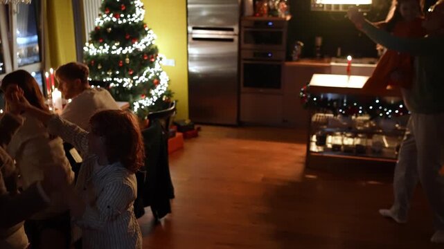 A grandson dances with his grandmother while behind him, his grandfather twirls his granddaughter in his arms while their family and guests sit at the table