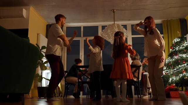 Mother and father dance with their son and daughter while guests and their grandparents sit at the table