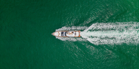 Naklejka premium Top aerial view on motorboat. Motor boat yacht floating to marina. Motorboat tour by summer sea. Luxury yacht boat at sea. Summer vacation. Luxury yacht boat top view. Blue ocean.