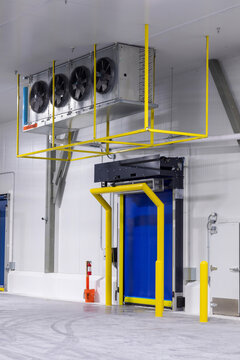 industrial cold storage room with large, ceiling-mounted  with evaporator fan units, used to remove heat from the room to maintain low temperatures, and High Speed Roll Up Doors  