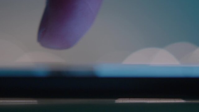 Scrolling Social Media Posts on Smartphone in Dark Ambience. Extreme closeup view of male finger scrolling up and down on the screen of a smartphone at night time. Shooting in slow motion. Selective f