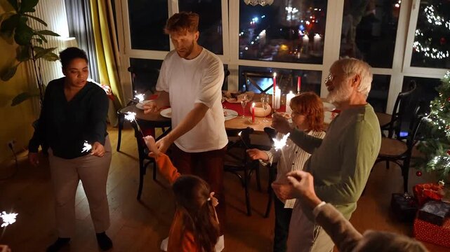 Family and guests dance while a woman gives them sparklers