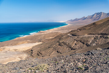 Panoramic view of the rugged coastline of Fuerteventura, Canary Islands, Spain, with turquoise Atlantic Ocean, sandy beaches and arid mountains under a clear blue sky.