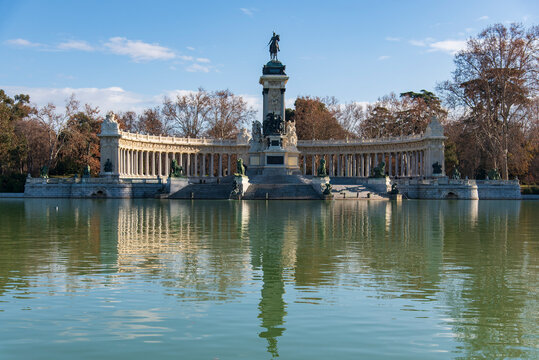 Monument to Alfonso XII at El Retiro Park in Madrid, Spain, neoclassical colonnade and equestrian statue reflected in the lake on a clear day.