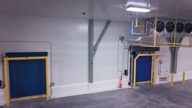 industrial cold storage room with multiple large, ceiling-mounted fixtures with evaporator fan units, used to remove heat from the room to maintain low temperatures