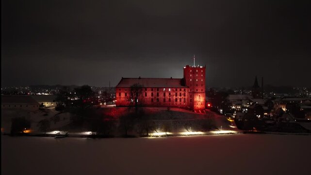 Winter night aerial of Koldinghus castle with snow covered lake, Denmark