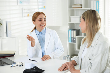 Fototapeta premium Woman having appointment with smiling cardiologist at table in clinic