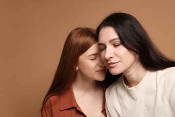 Mother and her teenage daughter on beige background. Space for text