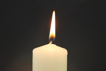 One burning candle on black background, closeup