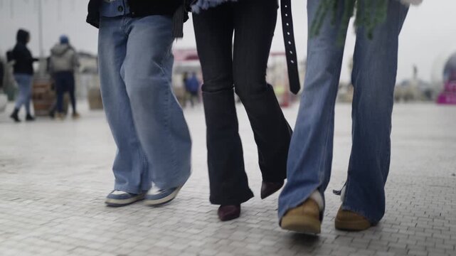 Three teenage girls walk together in an urban setting. Friends enjoy a casual stroll on a winter day.