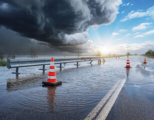 Flooded road with construction barrier and cones during storm and dramatic light