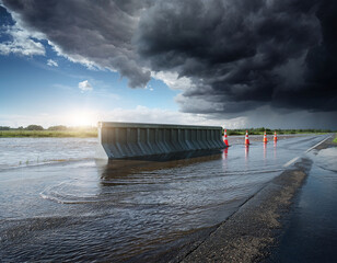 Flooded road with construction barrier and cones during storm and dramatic light
