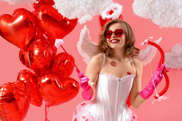 Naklejka premium Young woman dressed as Cupid with clouds and balloons on pink background Valentine's Day celebration