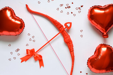 Naklejka premium Composition with red cupid's bow and heart shaped balloons on light background. Valentine's Day celebration