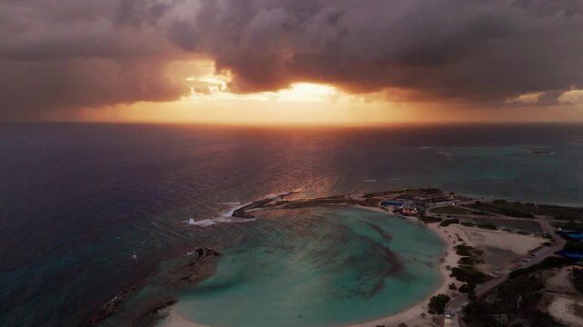 Vista a&eacute;rea cinematogr&aacute;fica del amanecer dram&aacute;tico y anaranjado en la playa de Baby Beach, Aruba / hermoso amanecer en la playa