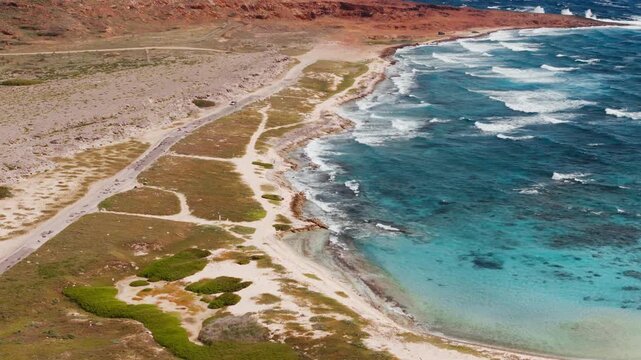 Toma a&eacute;rea de las olas rompiendo en la orilla de la playa blanca y agua azul turquesa cristalina con senderos hermosos en Aruba/ , toma de drone de una playa paradis&iacute;aca