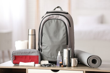 Emergency backpack, first aid kit and necessities on table at home