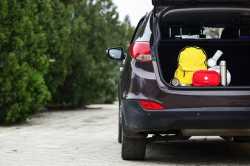 Emergency backpack, first aid kit and necessities in trunk of car outdoors