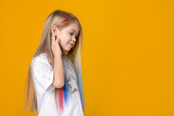 Cute girl with colorful clip-in hair extensions on yellow background. Space for text