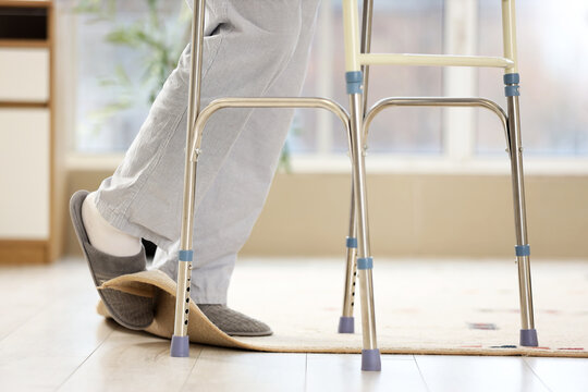 Legs of senior man with walker tripping over carpet at home