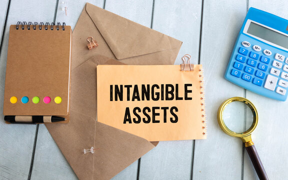 Intangible assets text on wood block on yellow notepad