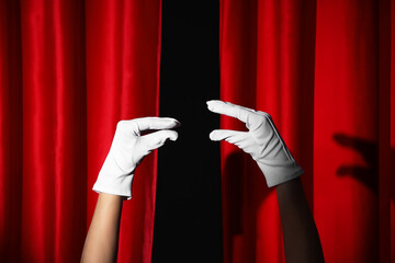 Female hands in gloves gesturing and red curtains on black background