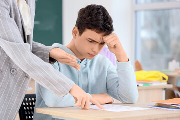 Female teacher scolding teenage boy for bad grade in classroom