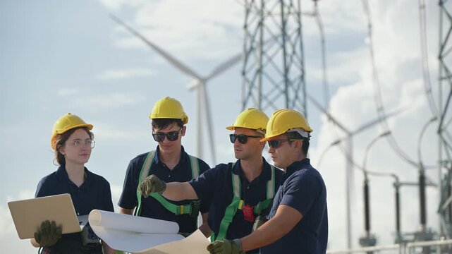 Engineers working on site in electricity substation. Technician wearing safety helmets inspecting in electricity substation at a wind turbine farm, Eco technology for electric, industry environment.