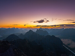 An aerial hyper lapse Layered Peaks and Valleys in a Calm Sunset Atmosphere. As the sun sets, dramatic clouds and fading light enhance the depth and beauty of the mountain highlands.