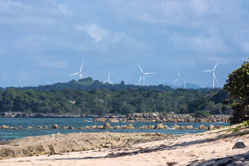 The sea coast and wind turbines are located on a hill.