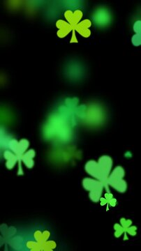 St Patricks day background with shamrocks in various greens floating outward on black. Three leaf clover particles drifting by for a green background to celebrate St Patrick day.