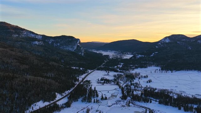 A drone pulls back from intricate ice patterns on a valley floor to reveal the vast Wolf Creek Colorado wilderness. This winter sunset shot highlights the cold alpine beauty of the Rockies.