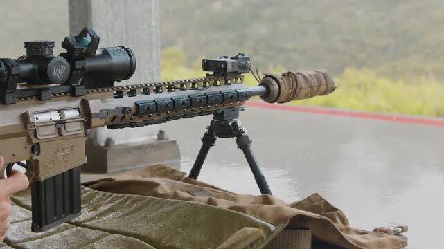 Close up, A Sniper Rifle being fired at a long range rifle club with the gunners fingers pressing the trigger and the rifle discharging, with gun powder smoke coming out the top.